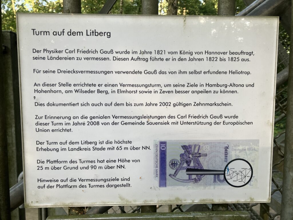 Texttafel:
Turm auf dem Litberg
Der Physiker Carl Friedrich Gauß wurde im Jahre 1821 vom König von Hannover beauftragt, seine Ländereien zu vermessen. Diesen Auftrag führte er in den Jahren 1822 bis 1825 aus.

Für seine Dreiecksvermessungen verwendete Gauß das von ihm selbst erfundene Heliotrop.

An dieser Stelle errichtete er einen Vermessungsturm, um seine Ziele in Hamburg-Altona und Hohenhorn, am Wilseder Berg, in Elmhorst sowie in Zeven besser anpeilen zu können.

Dies dokumentiert sich auch auf dem bis zum Jahre 2002 gültigen Zehnmarkschein.

Zur Erinnerung an die genialen Vermessungsleistungen des Carl Friedrich Gauß wurde dieser Turm im Jahre 2008 von der Gemeinde Sauensiek mit Unterstützung der Europäischen Union errichtet.

Der Turm auf dem Litberg ist die höchste Erhebung im Landkreis Stade mit 65 m über NN.

Die Plattform des Turmes hat eine Höhe von 25 m Über Grund und 90 m über NN.
Hier ist eine Bild eines 10 D-Mark Scheines mit dem Heliotrop abgebildet.

Hinweise auf die Vermessungsziele sind auf der Plattform des Turmes dargestellt.