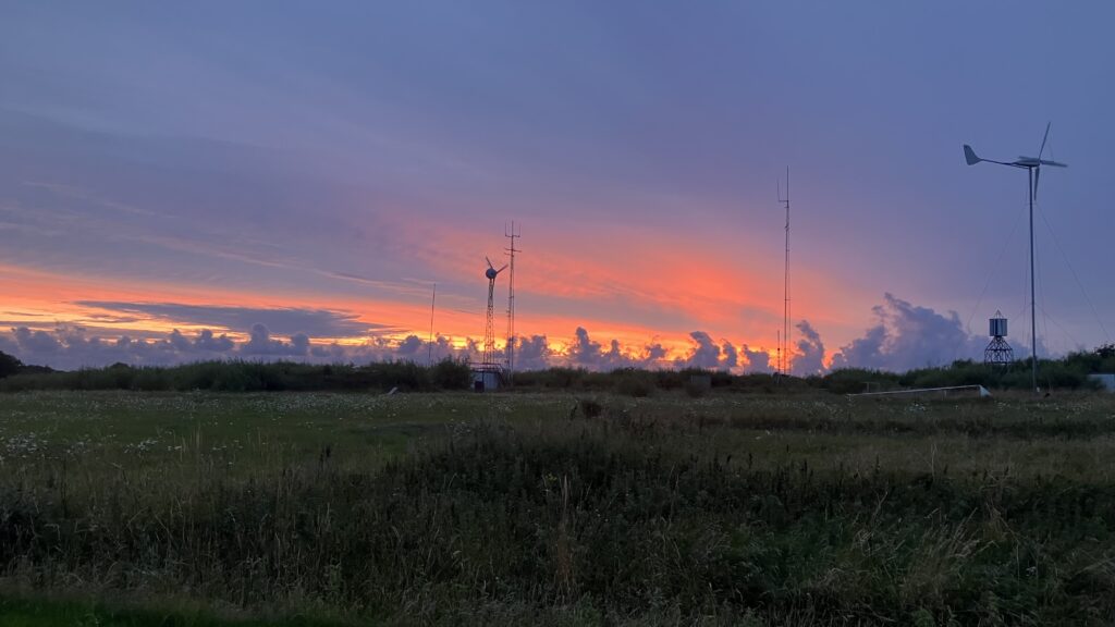Sonnenuntergang mit mehreren Windkraftanlagen im Vordergrund