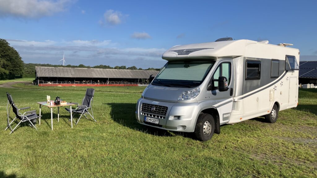 Unser Wohnmobil mit daneben stehenden Tisch und Stühlen